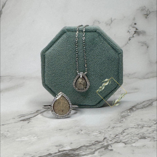 Large keepsake teardrop ring encompassed with faux diamonds paired with a keepsake teardrop necklace surrounded with faux diamonds. 